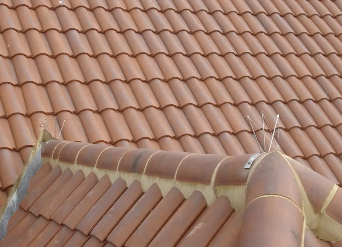 Mise en place d'un support de faîtage demi-rond sur une toiture arrondie.